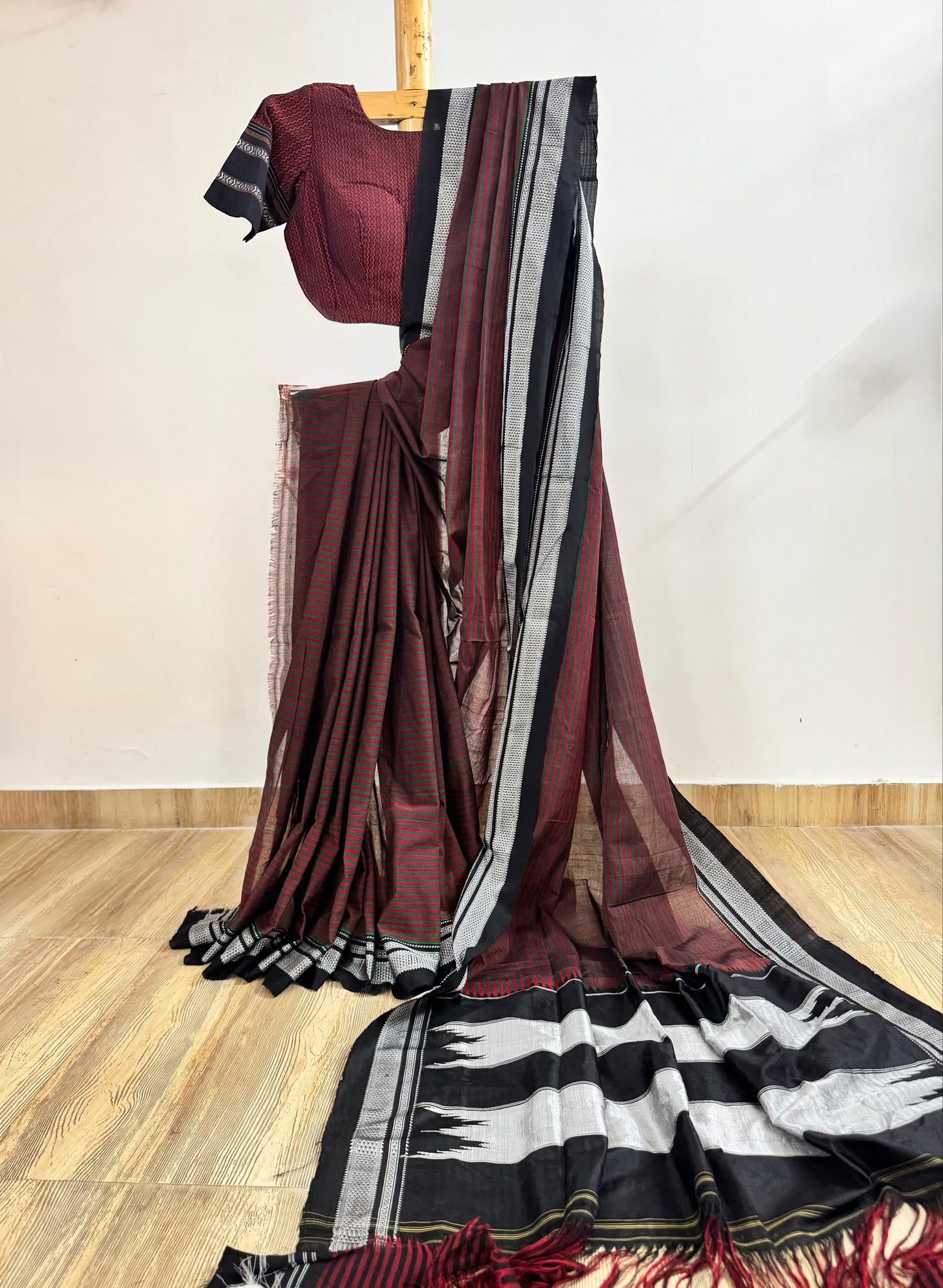 Maroon saree with black and white stripes on a wooden floor