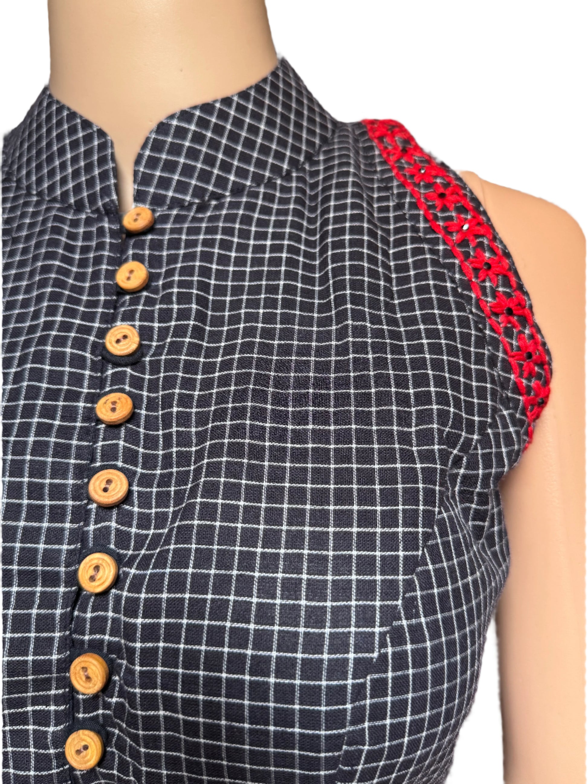 Black and white checkered blouse      with red lace trim and wooden buttons on a person.