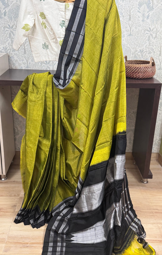 Green saree with black and white border draped over a chair in a room.
